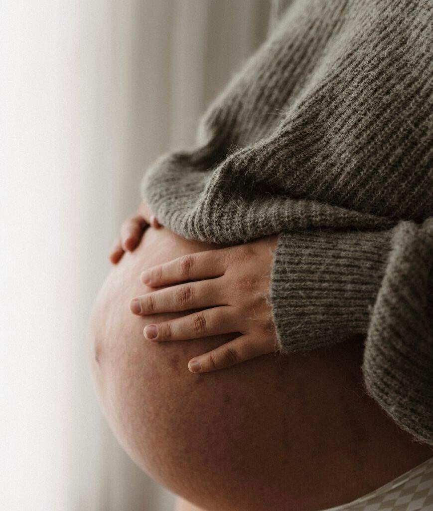Nahaufnahme der Hände einer Schwangeren auf ihrem Bauch – Hebammenbetreuung in Bonn